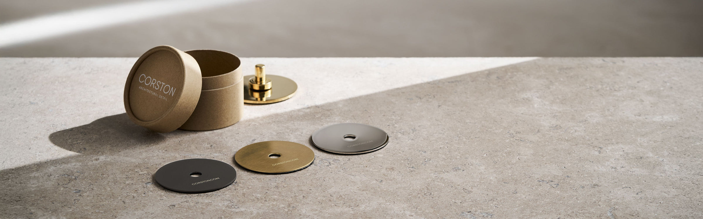 A hand selects a circular color swatch from a display of textured fabric samples in earthy tones and neutral shades.