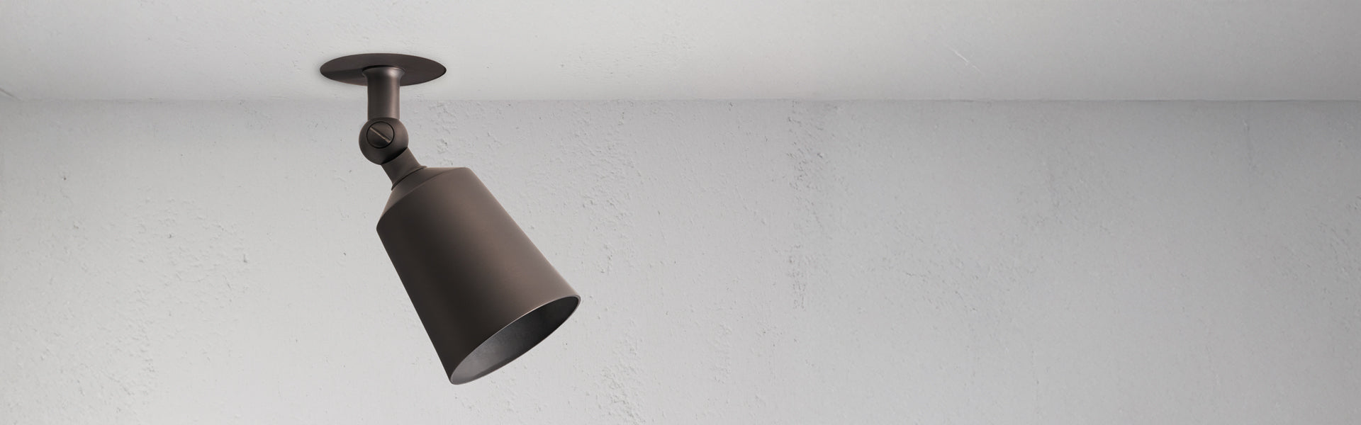 A single bronze black ceiling spotlight fixture is mounted on a white textured ceiling, angled downward toward the right.
