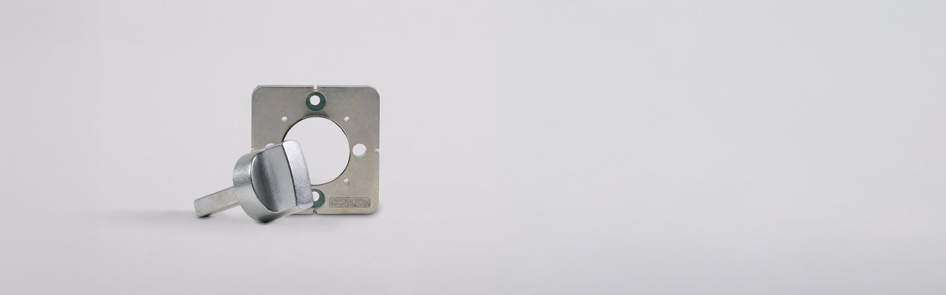 A metal key lies beside a square metal plate with a circular cutout, set against a plain white background.
