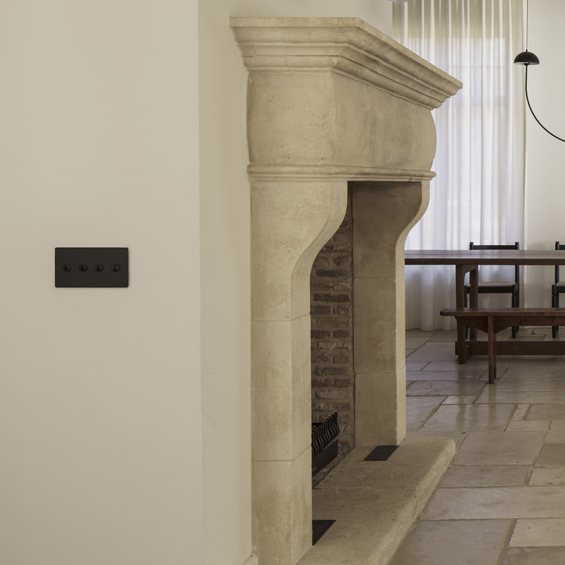 A modern living space featuring a stone fireplace, elegant wall sconces, and a minimalist dining area with a simple table and chairs.