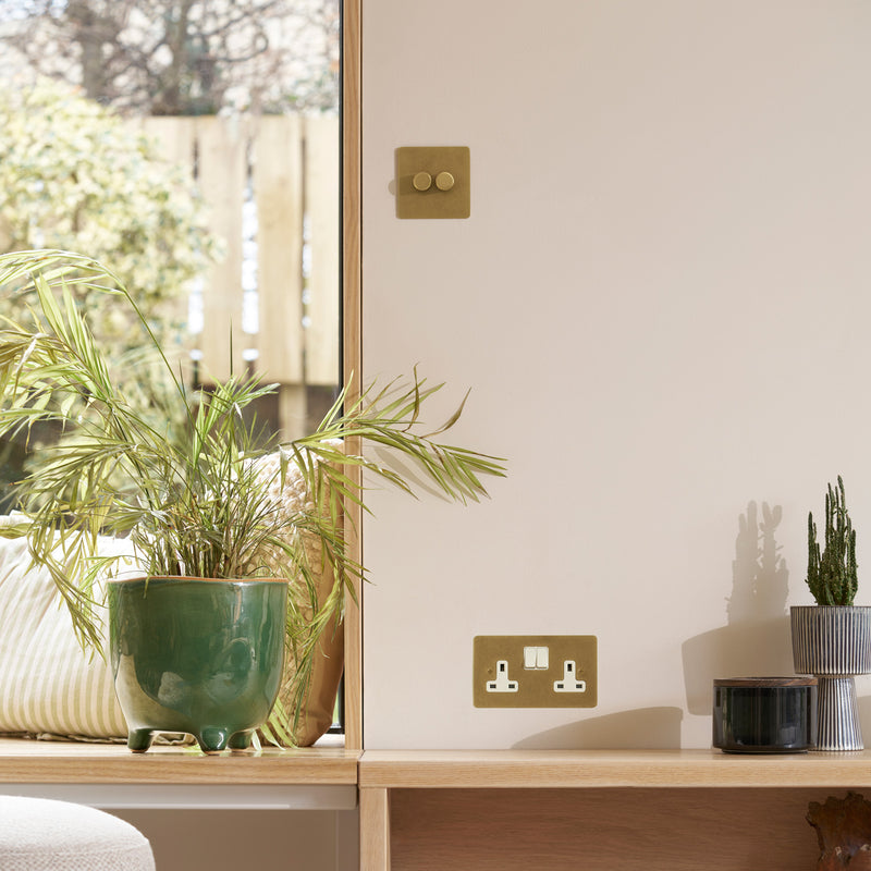 A cozy interior scene featuring potted plants, stylish wall switches, and natural light streaming in through a window.