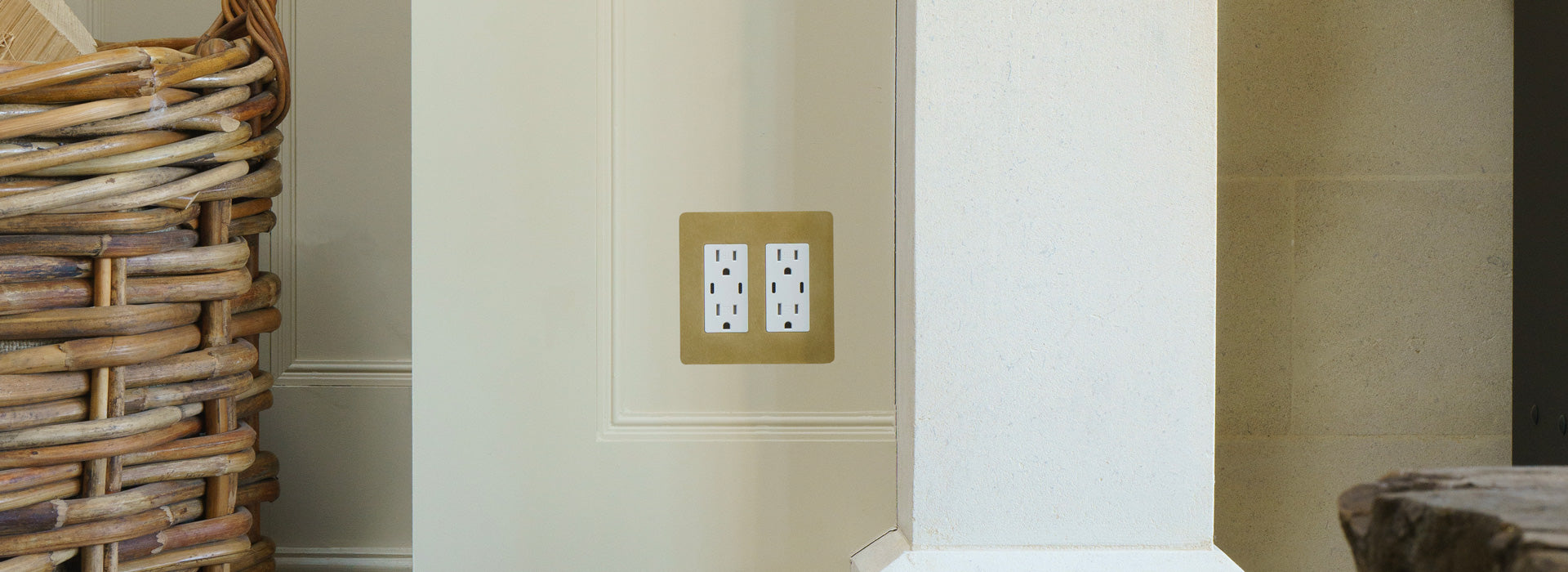 A decorative electrical outlet on a smooth wall beside a woven basket, blending functionality with interior design.
